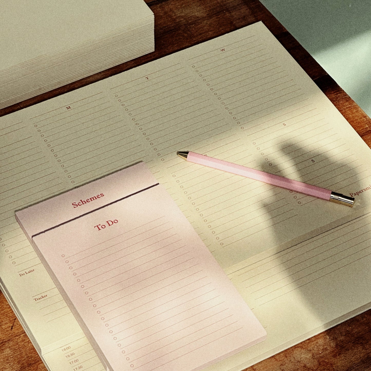 Open planner with a pink pen on a wooden surface