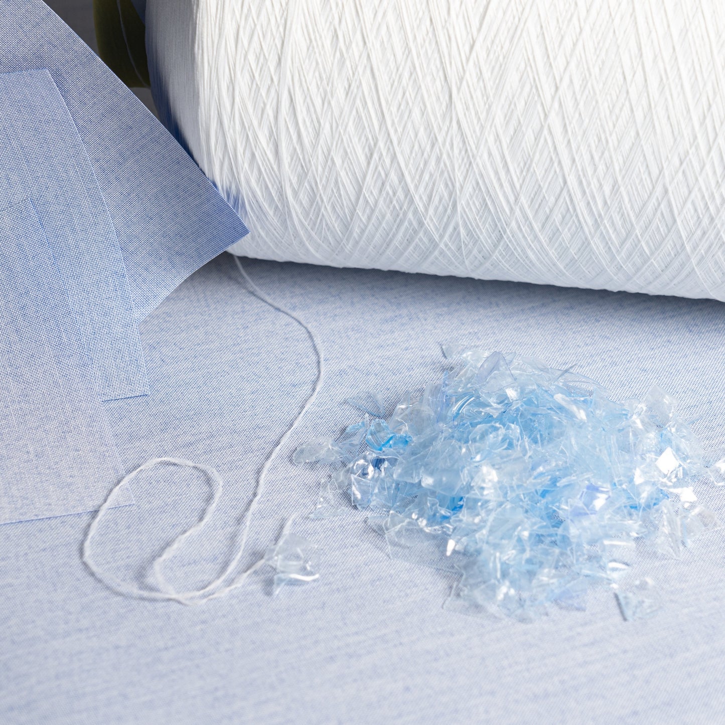 Close-up of white yarn on a textured surface with a small pile of yarn fibers.