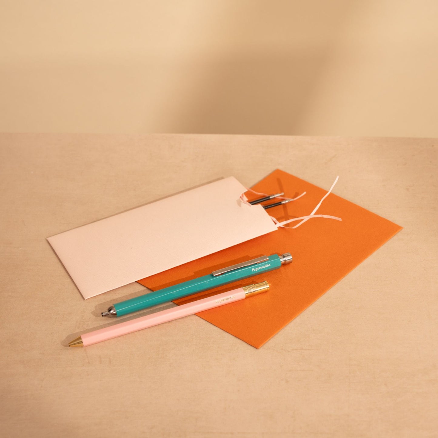 Two pens and a card on a beige surface