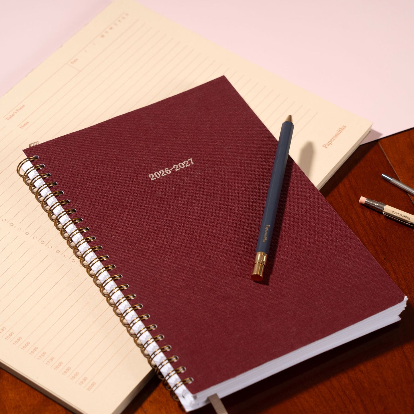 Maroon planner with a pen on a wooden surface