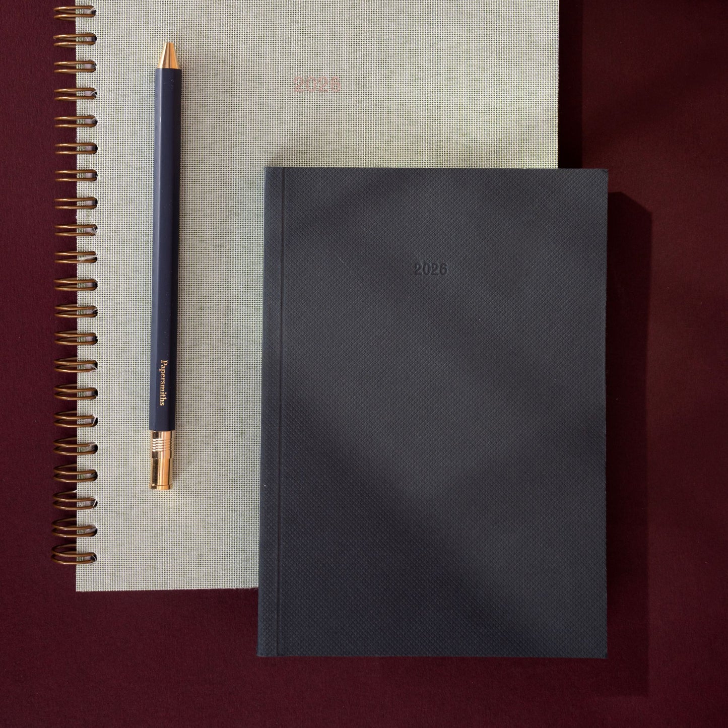 Black notebook and pen on a textured surface with a dark background