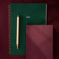 Two notebooks, one green and one burgundy, with a pen on a dark red background.