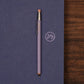 Purple pencil on a blue surface with a logo, on a wooden surface