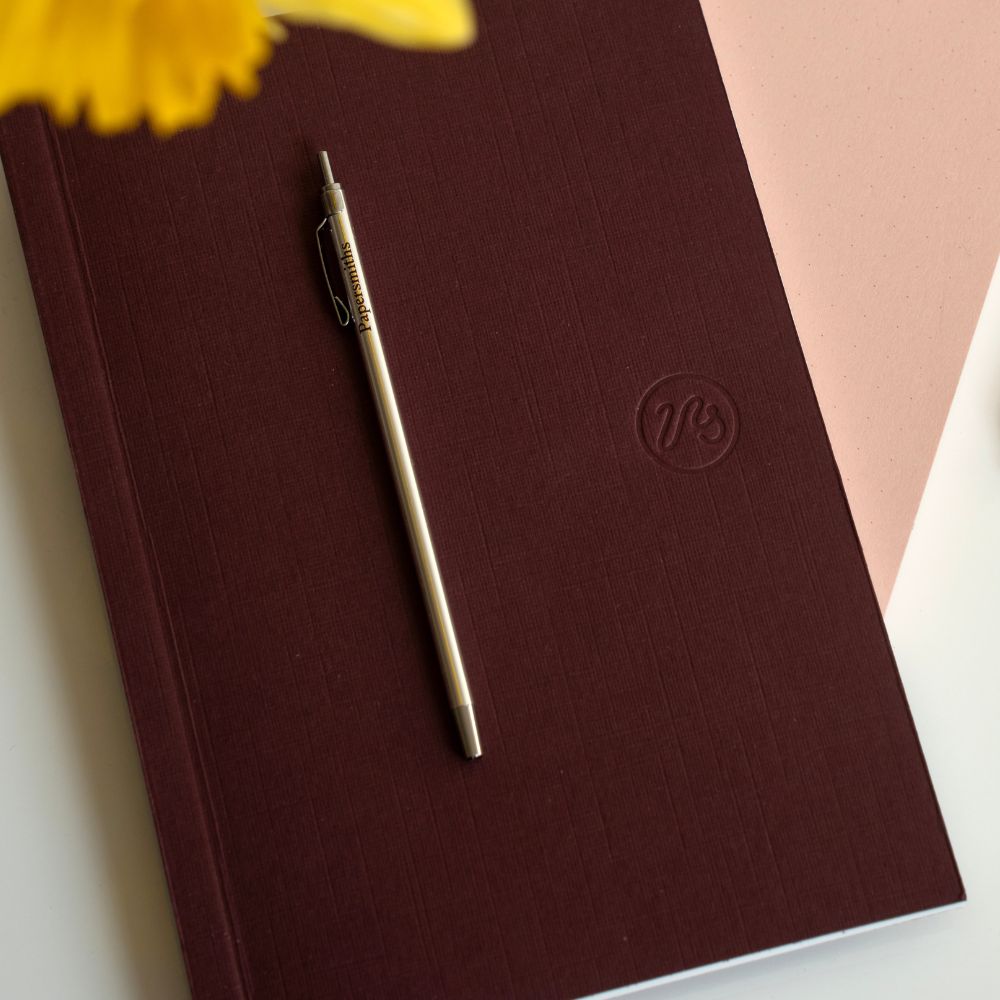 Pocket pen in silver lying on a pocket-sized notebook