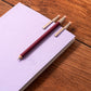 Three pocket pencils on a white notebook with a wooden surface background