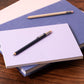 Two pocket pencils on top of a stack of notebooks on a wooden surface