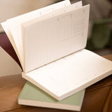 Open notebook 2026 diary pocket sized with lined pages on a wooden surface