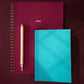 Two notebooks, one burgundy red and one blue, with a pen on a dark background